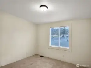 This secondary bedroom is filled with natural light and offers a pleasant view, making it a great choice for a home office or creative workspace.
