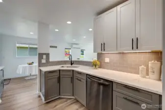 The kitchen features quartz countertops, new cabinetry, black stainless appliances, under cabinet lighting, offering both modern style and everyday functionality.