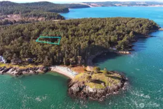 Wide aerial view showing the Cape San Juan neighborhood setting, nearby shoreline, and forested surroundings that frame this peaceful island homesite.