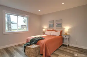 Primary bedroom with wood wrapped windows, recessed lighting and LVP flooring