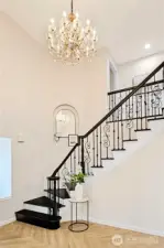 Vaulted entry with piano staircase and a luxury chandelier.