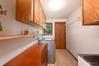 Well-equipped laundry area with a utility sink, plenty of storage, and backyard access