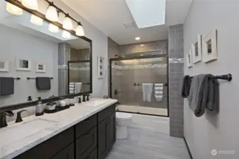 The main bath, remodeled in 2018, is similarly well-appointed with heated tile floors, a tile tub surround, a granite countertop, dual vanity sinks, a linen closet, and a skylight.