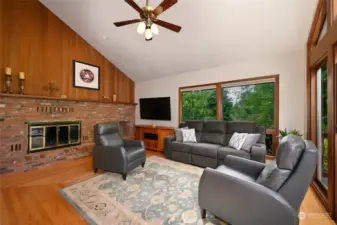 Across the hall, the family room offers a vaulted ceiling, another wood-burning fireplace with a brick surround and hardwood floors.