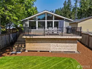 This view says it all: a spacious deck for cooking, dining, and lounging, with a wide staircase leading down to the lush backyard. The mid-century peaked roofline adds character, while the wall of windows in the family room brings the outside in. Plus, the partial fencing provides just enough privacy without losing that open feel.