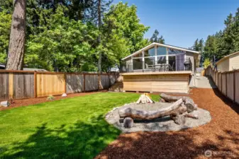 Your Backyard, Your Escape. Imagine this: a lush green lawn, perfectly level for all your outdoor activities, with a cozy firepit area that’s practically begging for marshmallow roasting. Log seating adds rustic charm, and the lake in the distance gives it that tranquil, “nature’s right outside” vibe. Lots of privacy with the new fence panels to give you lots of privacy for your chill moments.