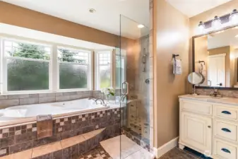 Jetted soaking tub in the ensuite with opposing His/Her's vanities.