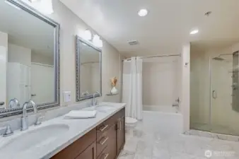 bathroom includes marble double vanity with marble floors and walk in shower