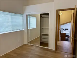 Mirrored closet doors and built-in organizer shelving make the most of the space—offering both function and style in this airy second bedroom.