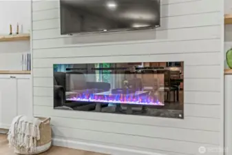 Ship-lapped feature wall w/electric linear fireplace and floating shelves atop built-in cabinetry...