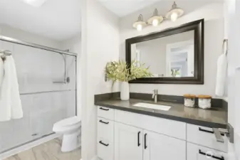 Remodeled bathroom with quartz countertops, tiled floor and new oversized walk-in shower.