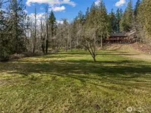 The large yard behind the home leads to the bridge that goes to the rest of the property.