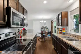 Granite countertops and deep warm tones compliment the galley-style kitchen, with two-basin under mount sink and a suite of stainless appliances the cook in your life will find this easy, step-saving kitchen layout a dream to work in!