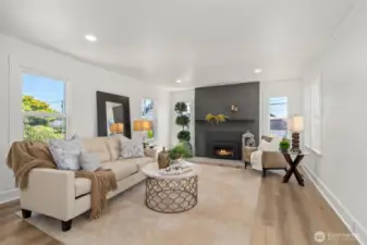 Spacious living room features a gas fireplace, new paint, floorin and lighting.