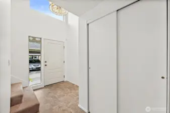 The entryway features a convenient coat closet for guests and soaring ceilings with windows that fill the space with natural light