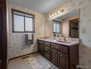 His and her vanities with pink sinks match the tiles and vintage soaking tub.