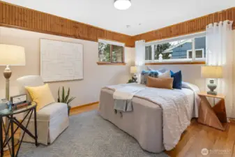 The 2nd bedroom retains its rustic feel, with hardwood floors and corner windows.