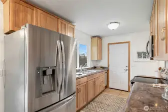 Roomy galley style kitchen with large window facing the backyard.