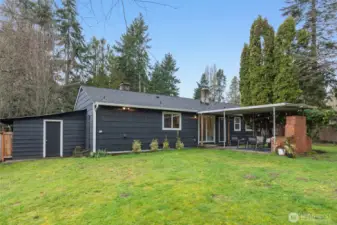 View of back of the home with covered patio and shed access.