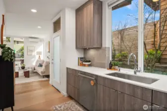 The finishes land in exactly the right place: sleek quartz slab countertops, a full tile backsplash, under-cabinet lighting, stainless appliances, induction cooking, wide-plank hardwood flooring, and a modern aesthetic that feels fresh without trying too hard. It presents like new because it basically is.