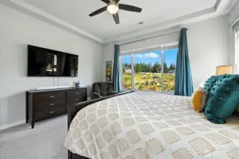 Primary bedroom with tray ceiling and ceiling fan