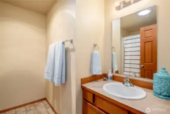 Shared bathroom between two bedrooms with tiled flooring and hardwood cabinets.