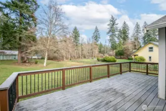 Expansive backyard, partially fenced with outdoor storage to the right of the deck.
