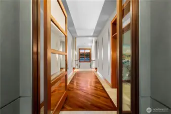 A striking arrival—custom woodwork, warm hardwoods, and a framed view drawing you toward the water.