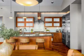 Chef’s kitchen with island seating, quartz countertops, custom cabinetry, and stainless steel appliances.