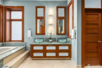 Well-appointed primary bath featuring dual vanities, vessel sinks, and custom cabinetry with stone surfaces.