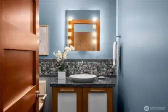 A jewel-box powder room—textured tile, stone surfaces, and statement lighting create a striking impression.