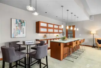 Stylish wet bar with custom cherry cabinetry, frosted glass inserts, and sea-glass countertops. Pendant lighting and bar seating create a welcoming space for casual dining or entertaining guests.
