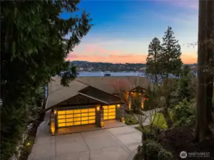 A dramatic evening arrival framed by soft lighting, lush surroundings, and sweeping views across Lake Washington.