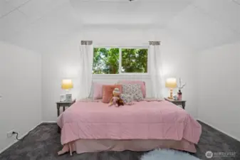 A cheerful upstairs bedroom with dormer ceilings and a peaceful view.