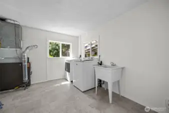 A dedicated laundry and utility space with newer appliances, a deep sink, and extra room for storage or projects.