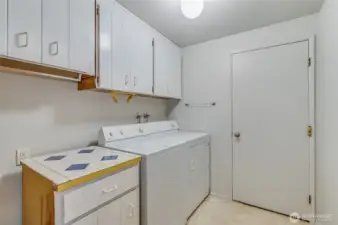 To the Right of the entry is the laundry room. Washer and Dryer stay! To the left of the folding table are the furnace, with A/C, and the brand-new water heater. Through the door in the background is where you will find the two car garage.