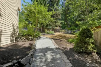 The wide side yard on the property. The backyard is fenced with gates on each side of the house.