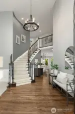 A soaring two-story foyer with a sweeping curved staircase makes a stunning first impression, while rich hardwoods add warmth and elegance to the space.
