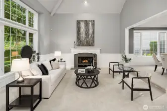 The elegant formal living room features soaring ceilings, expansive windows that flood the space with natural light, and a cozy fireplace - perfect for gatherings or quiet evenings.