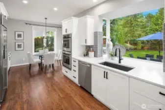 The spacious kitchen features premium stainless-steel appliances, a wine fridge, and custom cabinetry. Newly refinished solid hardwood floors add warmth and contrast to the crisp white cabinetry.