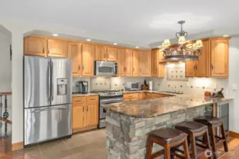 Gorgeous granite slab counters and extended stonework around peninsula with wine fridge, beautiful full tile backsplash