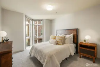 Large primary bedroom with memorable floor to ceiling windows.