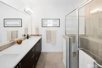 Primary bath features a double sink, oversized vanity, and glass-enclosed tile shower with seat.