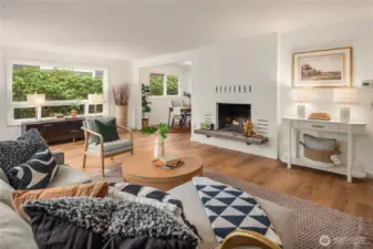 A wood burning masonry fireplace anchors the living room and is surrounded by large triple-pane windows.