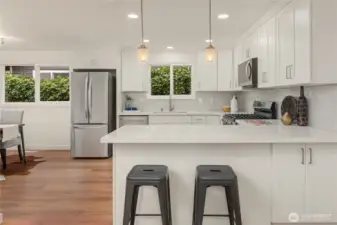 A breakfast bar with pendant lights looks across this extremely well laid out kitchen.