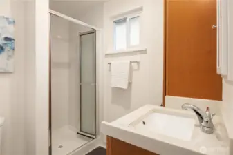 The primary bathroom features tiled floors and a tiled shower surround as well as a vanity with undermount sink and a tall storage cabinet.