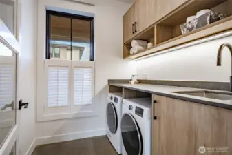 Laundry room with folding table, under cabinet lighting and large sink.