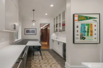 The kitchen also has a large eat-in banquette, a butlers pantry with additional storage and a wine refrigerator. The window above the banquette opens to the outdoor kitchen, providing easy access to getting food out to the grill.