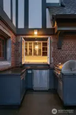 The outdoor kitchen includes a built-in barbecue connected to natural gas, a refrigerator, storage and a prep counter.