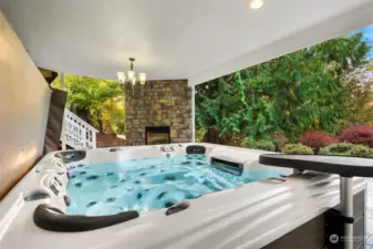 Partially covered patio with an outdoor fireplace and hot tub. A great place to relax and unwind.